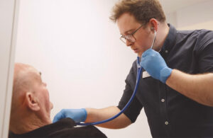 Man uses eMurmur-powered stethoscope to listen to a patient's heart.