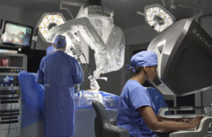 This is an Intuitive marketing image showing its da Vinci SP or single port robotic surgery system in use in an operating room.